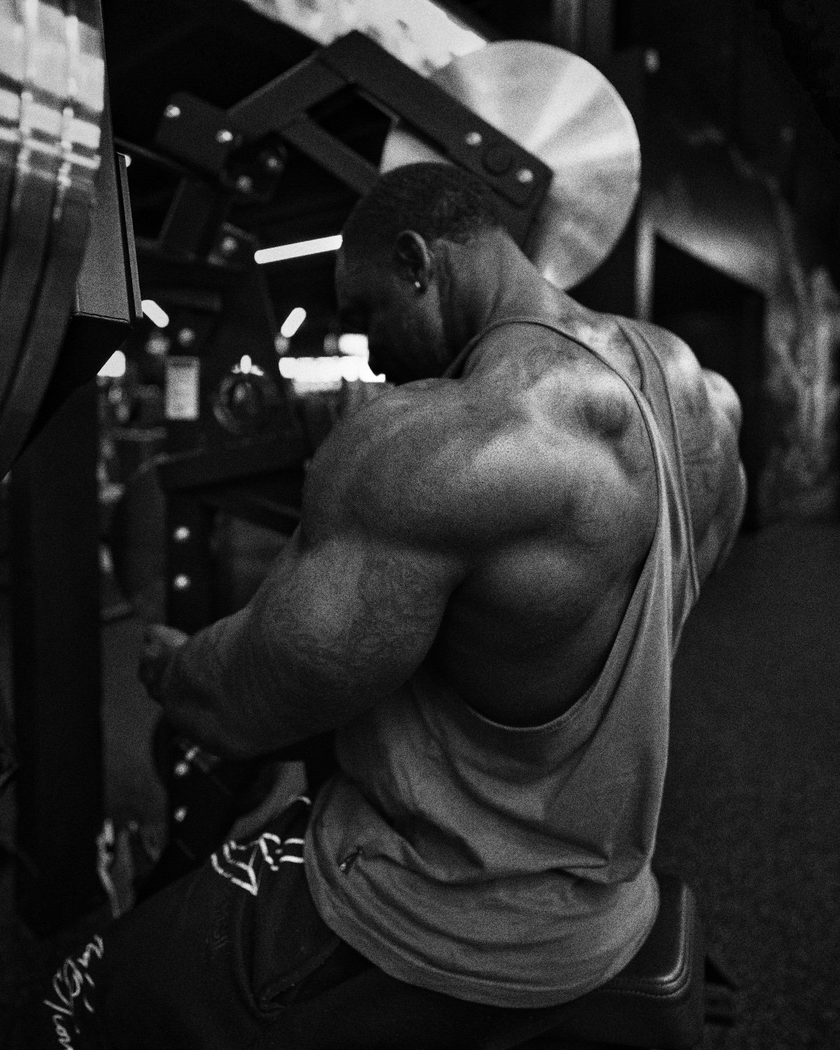 A bodybuilder trains his back on a machine in a dark gym